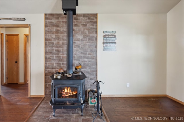 interior details featuring wood finished floors, baseboards, and a wood stove