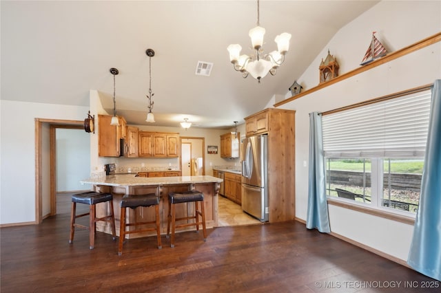 kitchen with visible vents, a chandelier, a peninsula, stainless steel appliances, and vaulted ceiling