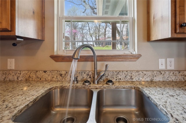 details with light stone countertops, a sink, and brown cabinetry