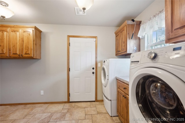 laundry area featuring visible vents, independent washer and dryer, stone finish floor, baseboards, and cabinet space