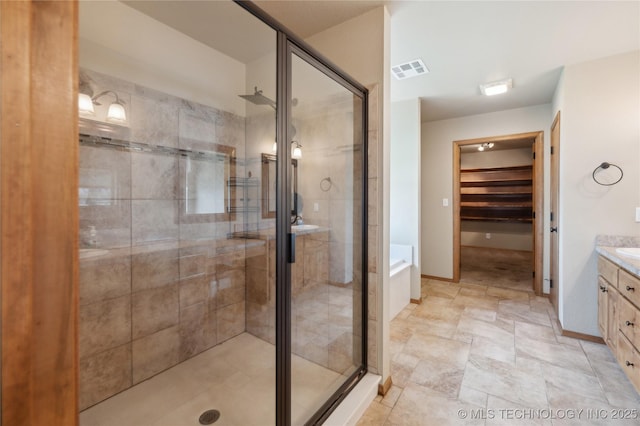 bathroom featuring visible vents, baseboards, vanity, a stall shower, and a garden tub
