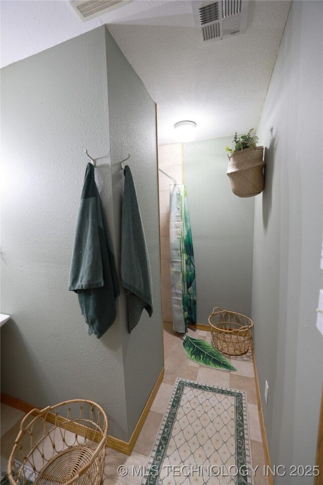 full bathroom featuring baseboards, a textured wall, visible vents, and a shower with curtain