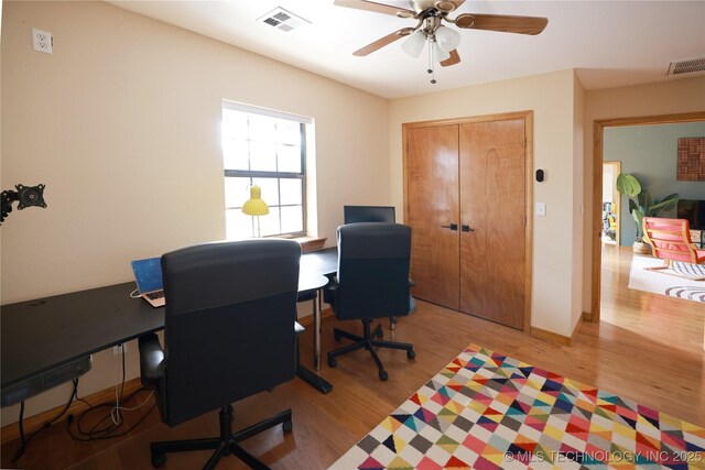 office space featuring a ceiling fan, wood finished floors, and visible vents