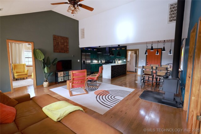 living area with visible vents, high vaulted ceiling, wood finished floors, and a ceiling fan