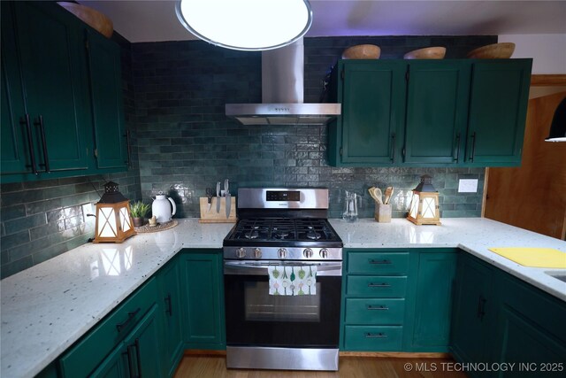 kitchen featuring wall chimney range hood, green cabinetry, stainless steel range with gas cooktop, and tasteful backsplash