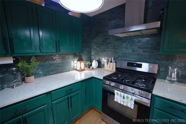 kitchen featuring wall chimney range hood, light stone counters, gas range, and tasteful backsplash