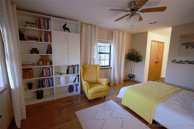 bedroom with a ceiling fan, wood finished floors, and visible vents