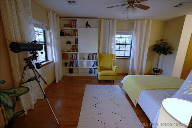 bedroom with wood finished floors, multiple windows, and visible vents
