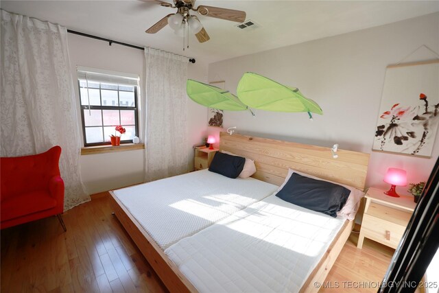 bedroom featuring visible vents, a ceiling fan, and wood finished floors