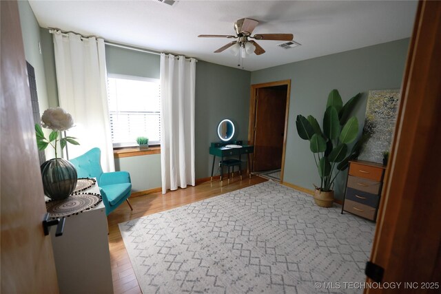 sitting room featuring a ceiling fan, wood finished floors, baseboards, and visible vents