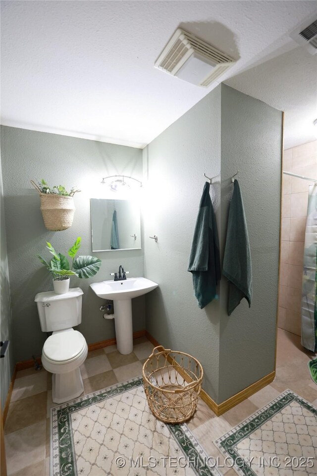 full bath featuring a shower with curtain, visible vents, toilet, and a textured wall