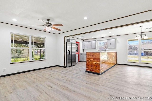 kitchen with stainless steel fridge with ice dispenser, ceiling fan with notable chandelier, a peninsula, and light wood finished floors