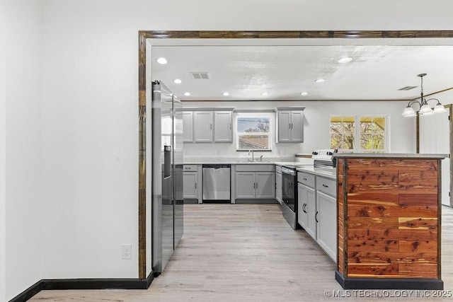 kitchen with visible vents, light wood finished floors, stainless steel appliances, a sink, and gray cabinetry