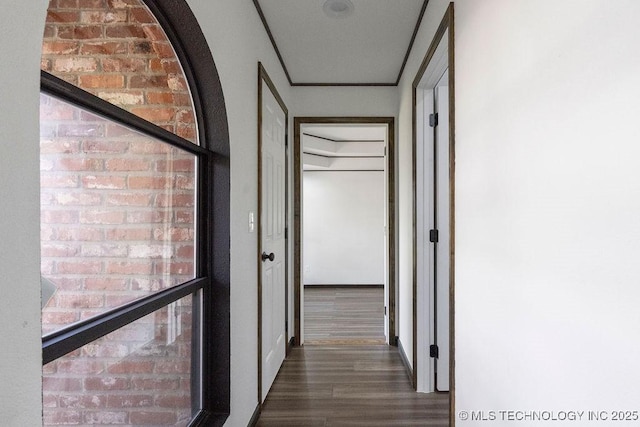 hall with wood finished floors and brick wall