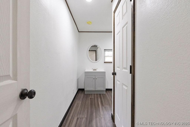 hall featuring baseboards, dark wood-style flooring, and a sink