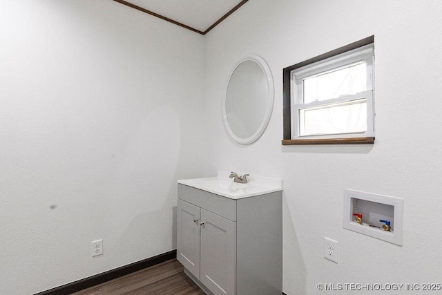 bathroom with crown molding, baseboards, wood finished floors, and vanity