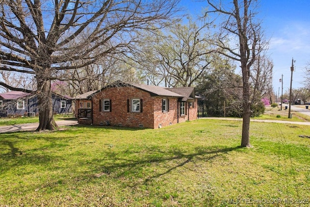 view of property exterior with brick siding, roof with shingles, crawl space, and a yard