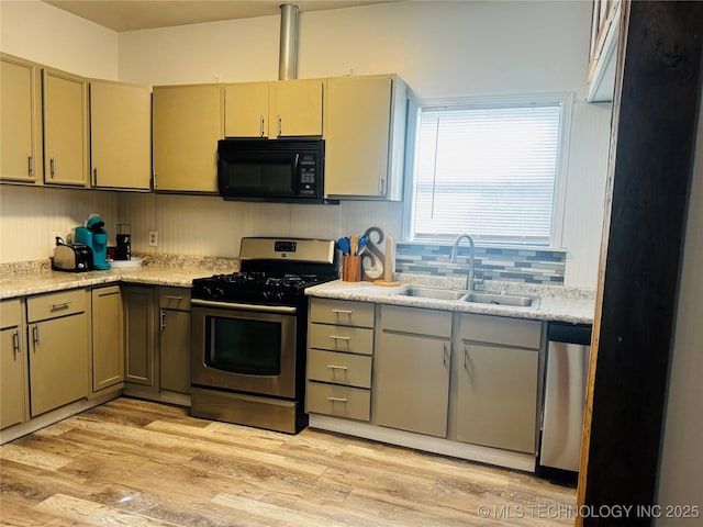 kitchen with a sink, light countertops, stainless steel appliances, light wood-type flooring, and tasteful backsplash