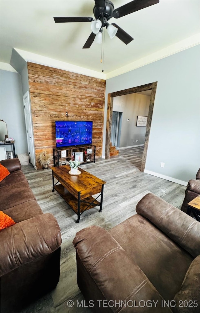 living area with baseboards, a ceiling fan, and wood finished floors