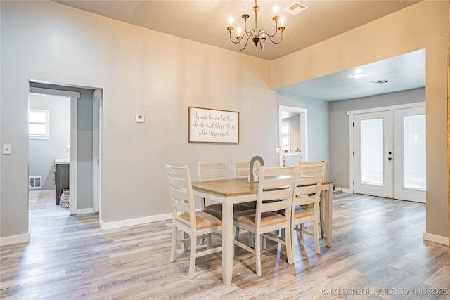 dining room featuring baseboards, visible vents, light wood finished floors, and a chandelier