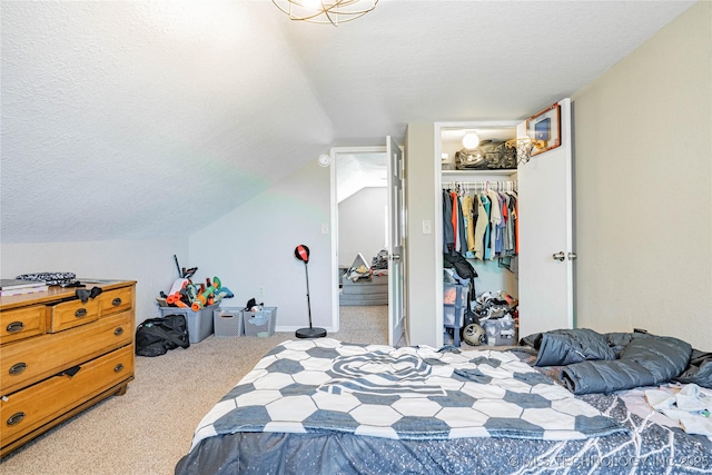 bedroom with carpet floors, a textured ceiling, vaulted ceiling, and a walk in closet