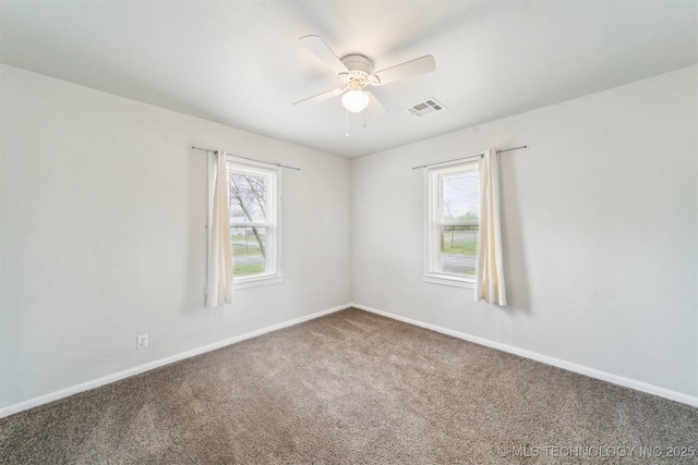 spare room featuring plenty of natural light, carpet floors, ceiling fan, and visible vents