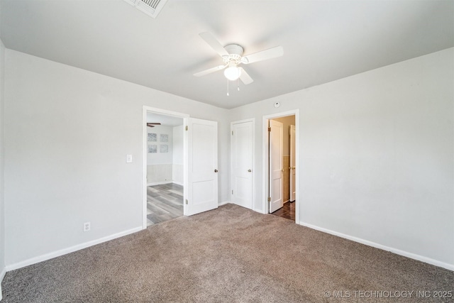 unfurnished bedroom featuring baseboards, carpet flooring, visible vents, and a ceiling fan