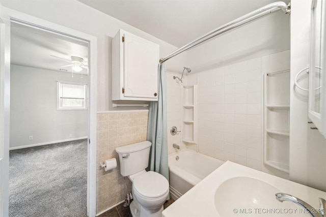 full bath with tile walls, shower / bath combo, toilet, a ceiling fan, and a sink