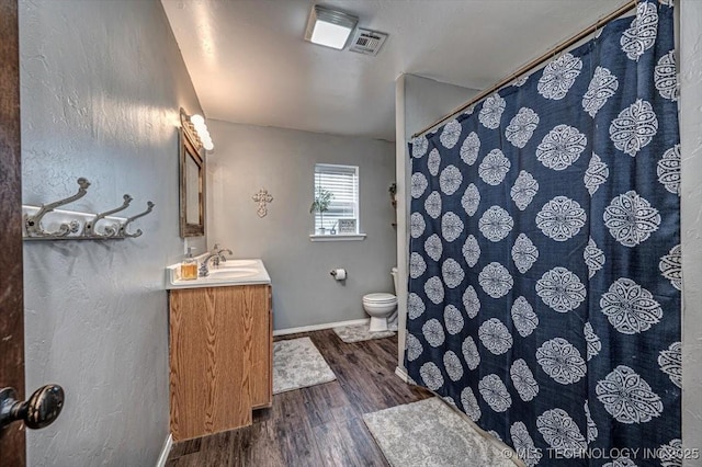 full bathroom with visible vents, baseboards, toilet, wood finished floors, and vanity