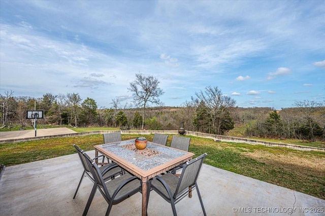 view of patio with a wooded view and outdoor dining space