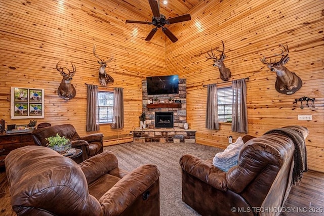 living room featuring a fireplace, ceiling fan, a high ceiling, and plenty of natural light