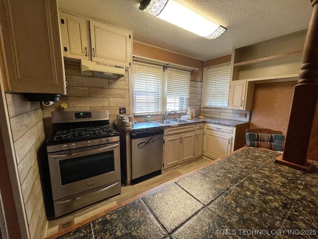 kitchen featuring a sink, tile counters, a textured ceiling, stainless steel appliances, and backsplash