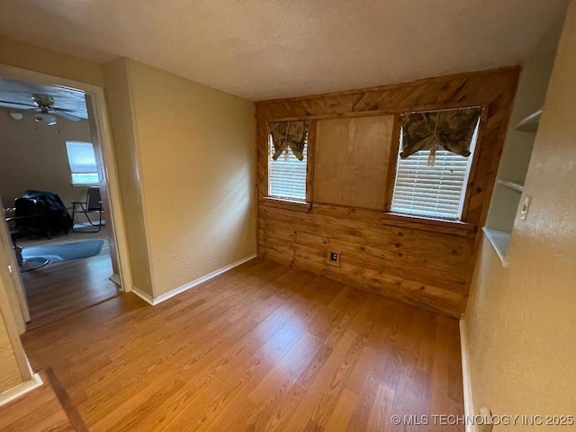 empty room with light wood-style floors, a ceiling fan, and a wealth of natural light