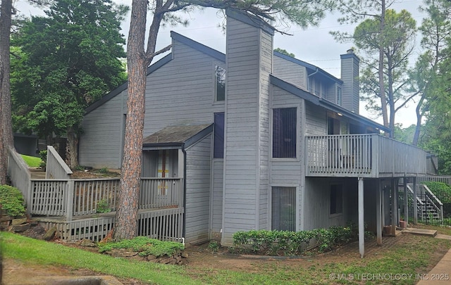 7502 S Winston Pl Unit 203, Tulsa, OK 74136 - back of property with a chimney, a wooden deck, and stairway