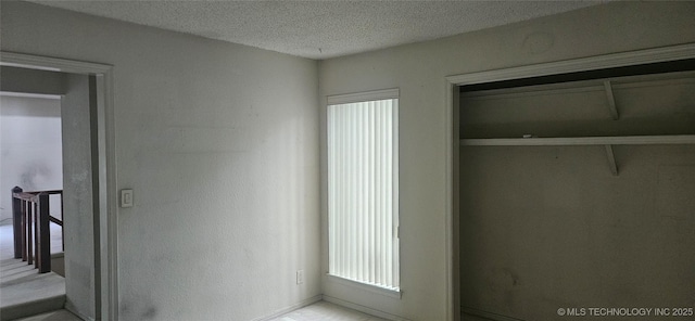 7502 S Winston Pl Unit 203, Tulsa, OK 74136 - unfurnished bedroom featuring a textured ceiling and baseboards