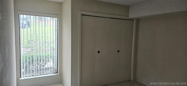7502 S Winston Pl Unit 203, Tulsa, OK 74136 - unfurnished bedroom featuring multiple windows, a closet, and baseboards