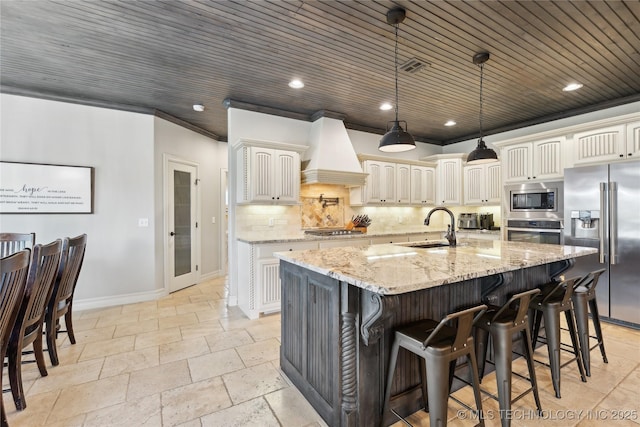 19672 E 69th St N, Owasso, OK 74055 - kitchen featuring appliances with stainless steel finishes, a sink, custom range hood, baseboards, and stone tile flooring