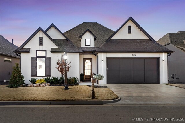 modern farmhouse style home featuring stucco siding, concrete driveway, roof with shingles, and a garage