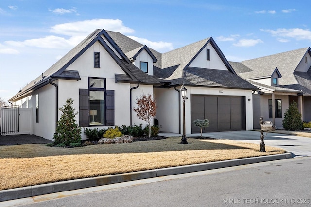 view of front of house with a front lawn, concrete driveway, fence, an attached garage, and stucco siding