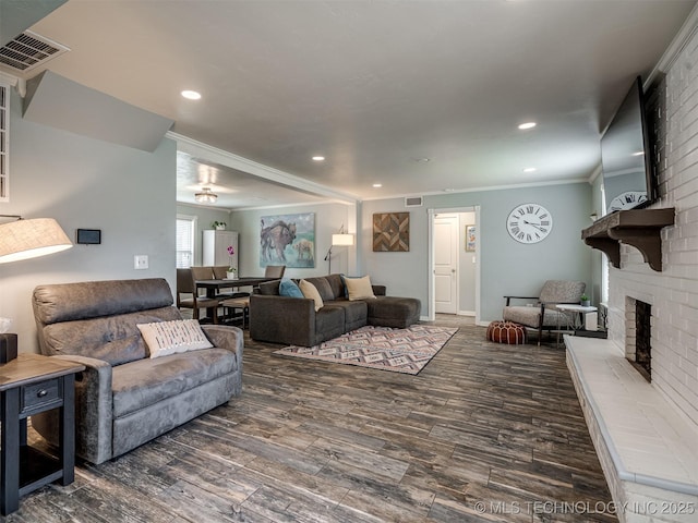 living area with wood finished floors, a brick fireplace, and visible vents