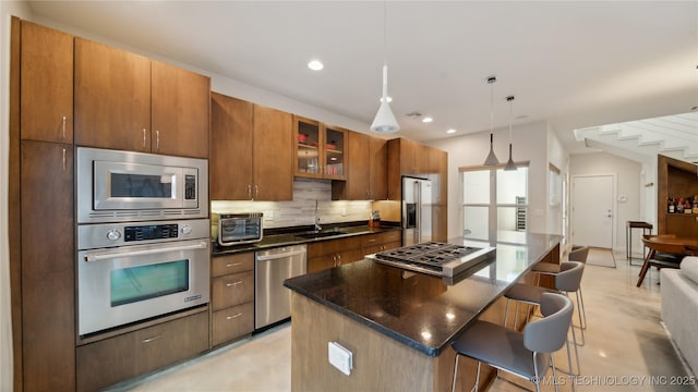 kitchen with tasteful backsplash, a sink, appliances with stainless steel finishes, a breakfast bar, and a center island