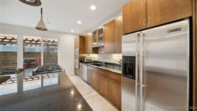 kitchen featuring decorative backsplash, glass insert cabinets, a sink, stainless steel appliances, and recessed lighting