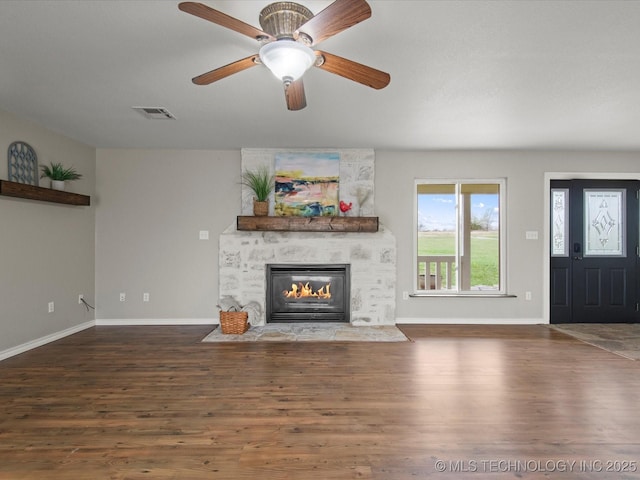 unfurnished living room with a large fireplace, visible vents, baseboards, and wood finished floors