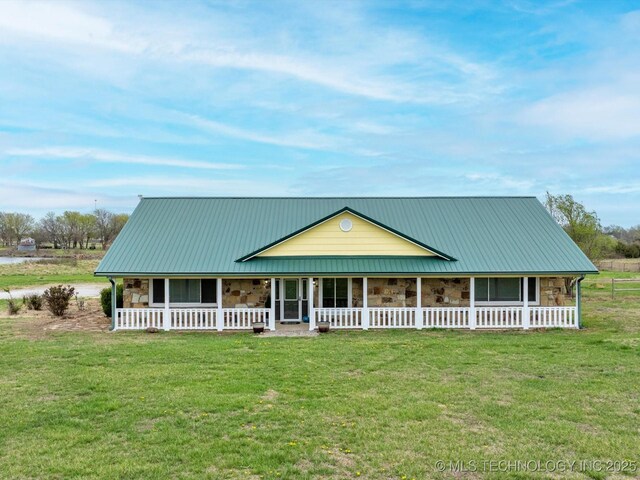 farmhouse with metal roof, a front yard, a porch, and stone siding