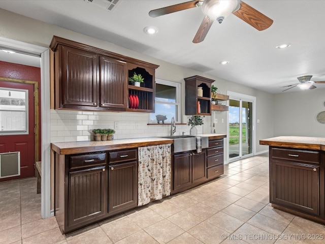 kitchen featuring decorative backsplash, a ceiling fan, dark brown cabinetry, a sink, and open shelves