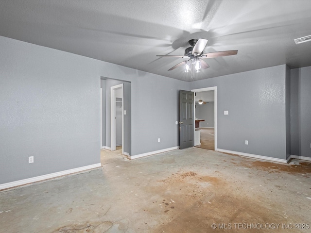 unfurnished bedroom featuring visible vents, baseboards, ceiling fan, unfinished concrete floors, and a walk in closet