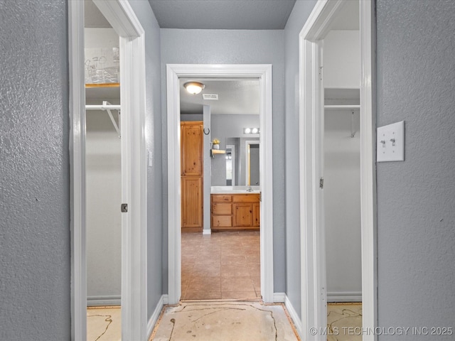 corridor featuring a textured wall and visible vents