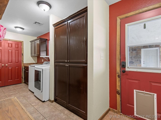 clothes washing area featuring washer and clothes dryer, light tile patterned floors, baseboards, visible vents, and cabinet space