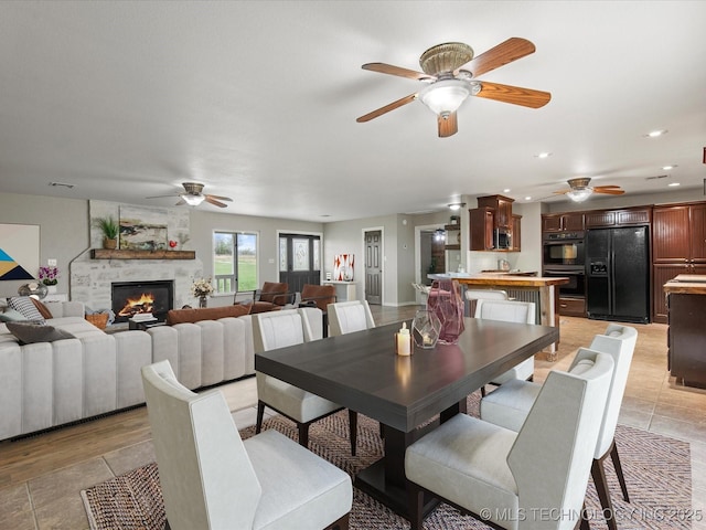 dining space with ceiling fan, recessed lighting, light tile patterned floors, and a stone fireplace