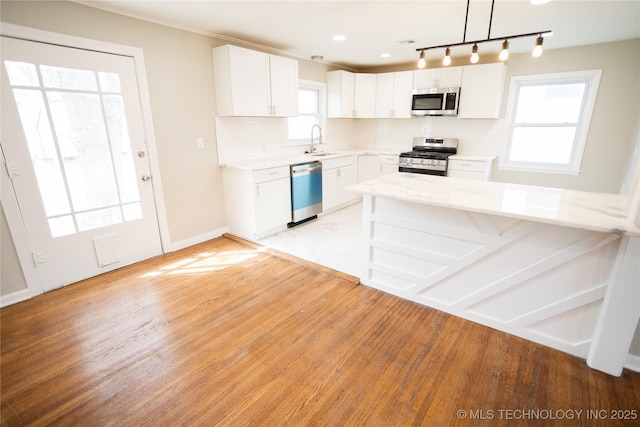 5760 E 29th St, Tulsa, OK 74114 - kitchen featuring white cabinets, appliances with stainless steel finishes, a sink, light wood-style floors, and a wealth of natural light